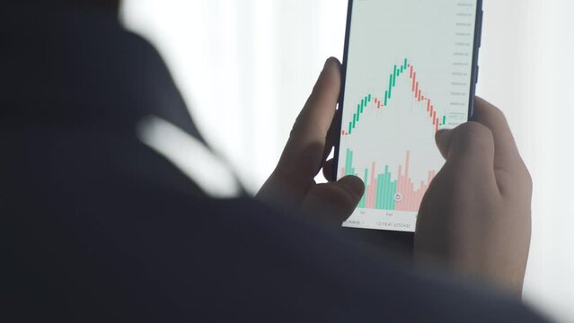 Close-up view of stock market and cryptocurrency charts from phone.
Close-up of man looking at stock market, stock, investment charts from phone.
