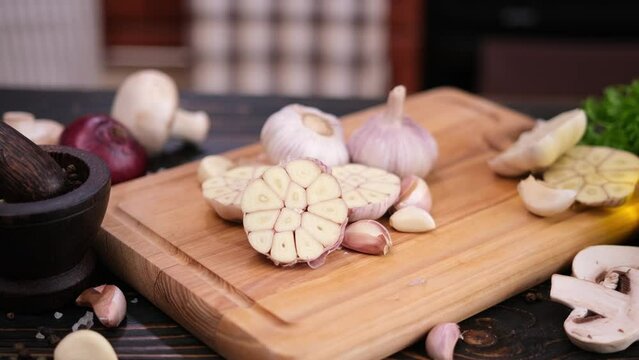 sliced halved garlic on wooden cutting board at domestic kitchen
