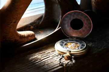An image of an old dusty vintage pocket watch resting on a dark wooden window ledge.