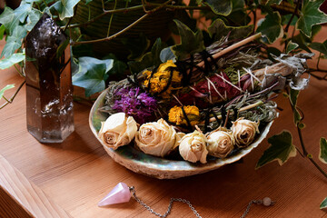 An image of an abalone shell filled with healing smudge sticks and dried rose bud flowers. 
