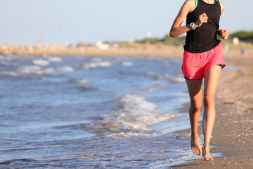 athletic girl running on the beach by the sea to train