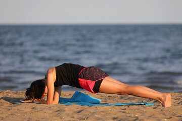 girl standing motionless in the position called Plank during gymnastic exercise by the sea