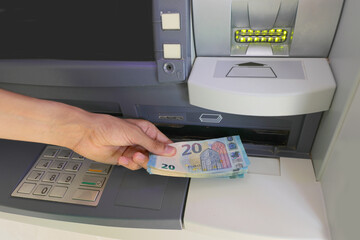 Hand picking up European € 20 banknotes from the bank ATM