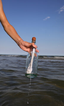 hand picking up the glass bottle with a message inside it just arrived from the sea