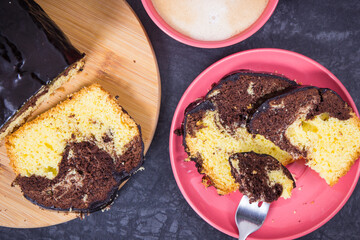 Fresh baked yeast dough with cocoa and chocolate icing, cup of coffee with milk. Delicious dessert