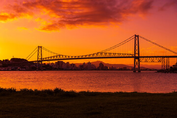 Fototapeta na wymiar Cable bridge with sunset sky and reflection on water in Florianopolis, Brazil