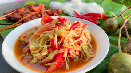 Som Tam Thai - Thai Green Papaya Salad with Grilled chicken over banana leaf