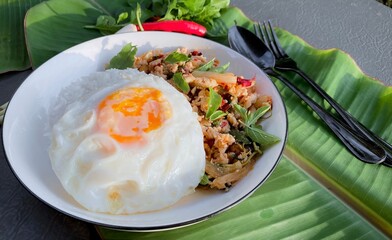 Chicken Basil and Fried Egg with  laid on top of banana leaves.