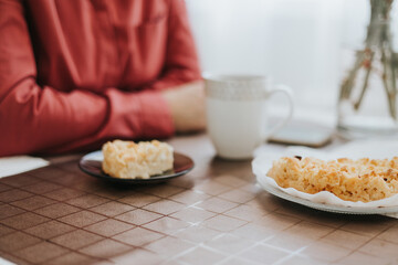 middle-aged woman sitting at the table in the cosy kitchen in the apartment and drinking tea with apple pie, cozy autumn days