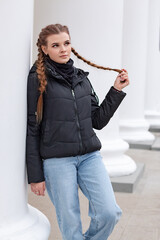 A young girl stands in front of white columns.