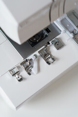 White modern ewing machine and its components close up. Sewing needle plate and replacement parts
