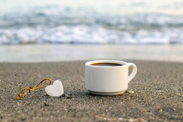 coffee cup on sands beach or big seashore rocks stone against sea ocean lake splashing water...