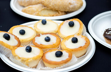 a lot of cupcakes dessert, bucket in glass on shelf or table outside street foot festival city national day.blueberry walnut decoration buns on plate, cake with whipped cream sugar unhealthy fats.