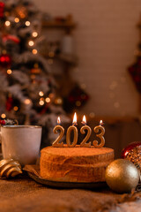 homemade honey cake in the kitchen with candles 2023. Cozy New Year at home. Merry Christmas