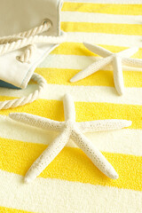 Fototapeta na wymiar The concept of travel, vacation, summer, beach items, resort hotel, bath eco decor, spa. On a striped yellow towel lies a canvas bag and starfish. Copy space. Nobody.