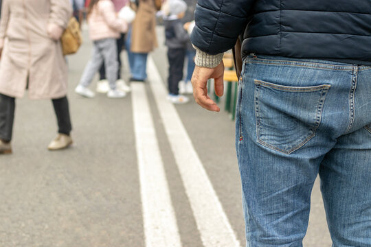 Man Hand Leg Back View On Double White Line Close Up Lot Of People Walking In Middle Of Road Street Different Directions.city Day Festival Urban National Day Barbeque Street Food. Finger Like Thumb Up