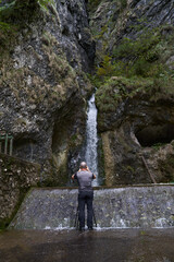 Nature photographer with camera by a waterfall