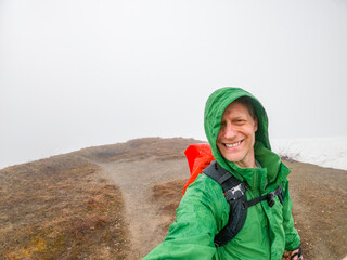 Adventurous athletic male hiker taking a selfie on a hiking trail in early spring on a cloudy day...