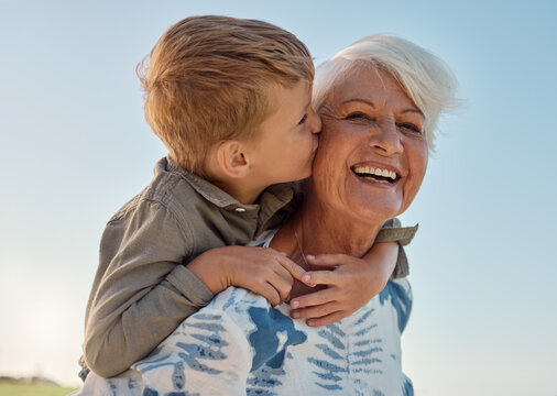 Kiss, child and grandmother in a park with love, care and freedom for happiness in retirement. Senior, smile and portrait of a woman with hug from a kid and kissing in nature or park with piggyback - Powered by Adobe