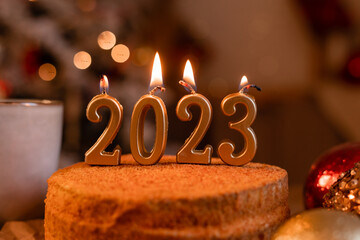 homemade honey cake in the kitchen with candles 2023. Cozy New Year at home. Merry Christmas. High...