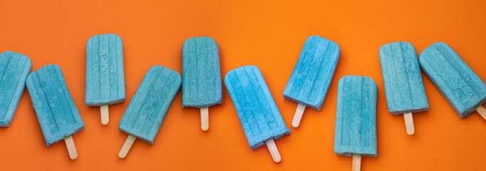 some blue popsicles on a orange background for banner, panorama, border