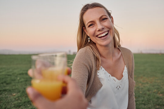 Cheers, Juice And Portrait Of A Happy Woman In Nature On An Outdoor Picnic In A Garden With A Summer Sunset. Happiness, Smile And Pov Of A Lady Toasting With A Orange Drink While On A Romantic Date.