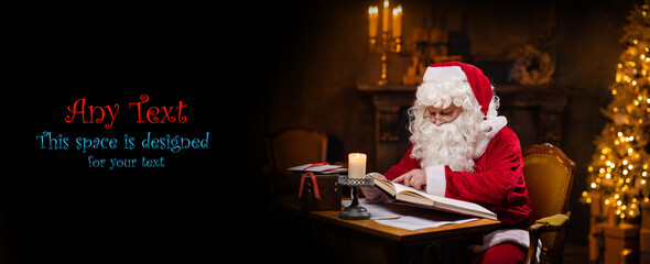 Workplace of Santa Claus. Cheerful Santa is reading the book of wishes while sitting at the table....