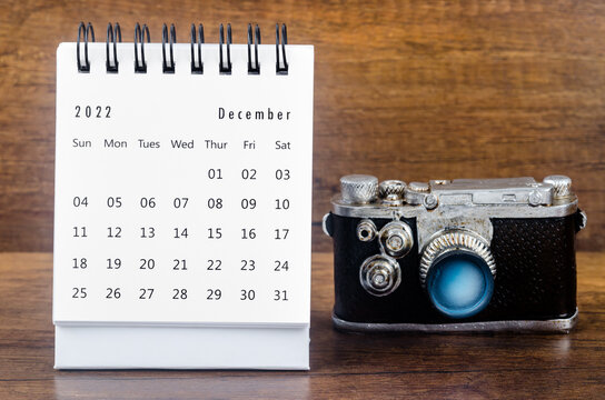 The December 2022 Monthly desk calendar for the organizer to plan 2022 year with a vintage camera against a wooden table background.