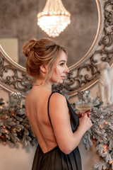 Portrait of a wealthy mature woman with evening makeup and hairstyle posing in a black dress against the backdrop of a Christmas room. Luxurious lifestyle. Cosmetology, plastic surgery, rejuvenation.