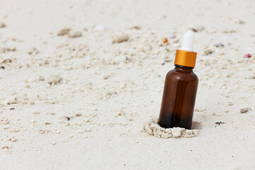 dark amber glass bottles with oil on sand. natural cosmetics product, beauty and presentation concept , mock up. relax and vacation style copy space