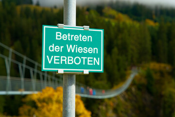 Green German road sign with the text: Forbidden to walk on the lawn