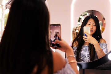 young woman taking a picture with her mobile phone of her new haircut and hairstyle in the...