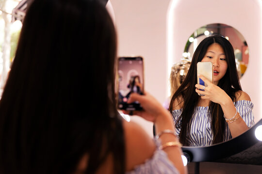 young woman taking a picture with her mobile phone of her new haircut and hairstyle in the hairdresser's salon mirror, beauty care and wellness concept