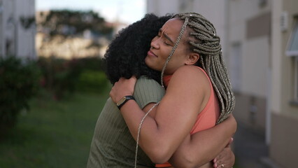 Two happy Brazilian black women laughing and smiling together. Fun adult girls embrace standing outdoors. Friendship concept