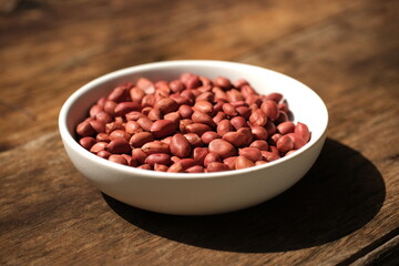 Organic peanut in white bowl on wood table