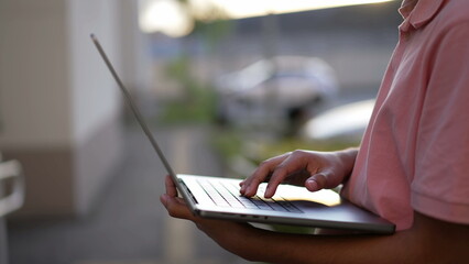 Obraz premium Closeup person hands holding laptop standing outdoors. Young man using computer working remotely