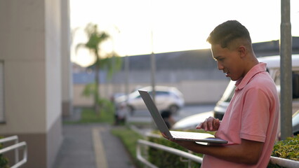 A hispanic young man turning computer ON. Person opening laptop sitting outside works remotely