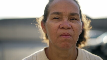 One mature hispanic woman stands outdoors with serious emotion. South american older latin female senior Brazilian person