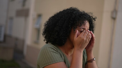 One crying young black woman covering face in despair. Tearful sad African American adult girl