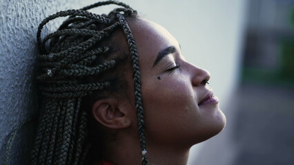 Meditative young woman eyes closed relaxing outside. A pensive hispanic black Brazilian with restul peace of mind