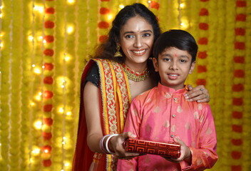 Fototapeta na wymiar Happy young woman and son celebrating diwali holding plate of diyas,gift boxes