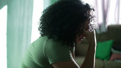 A worried black woman feeling anxiety at home. African American person suffering alone from negative emotions