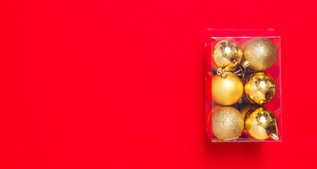 Golden Christmas balls-toys are packed in a transparent plastic box. Preparing for the Christmas holidays. Banner for a store selling Christmas decorations. Post-holiday cleaning