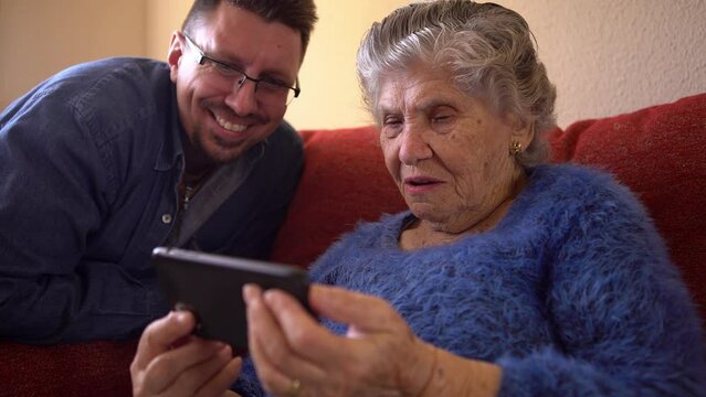 Happy cheerful elderly grandma woman speaking to family on video conference call, talking to grandchildren online on sofa at home. Family relationship concepts