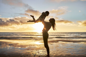 Mother, girl and sunset silhouette at beach while play, lift and love during summer vacation in Hawaii. Woman, child and energy with fun, carry and care during family travel holiday at Hawaii sea