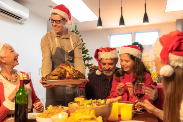 father in santa hat carving chicken at christmas dinner at home.Family having holiday dinner and cutting turkey Thanksgiving Celebration Tradition Family Dinner Concept