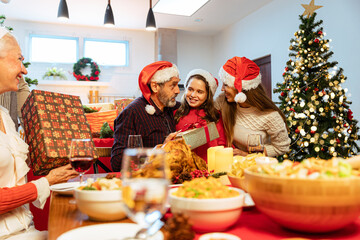 Happy family celebrating Christmas with Grandparents .Family make surprise for happy grandfather on Christmas , granddaughter gives xmas present .