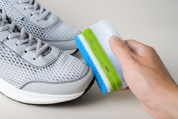 Close-up of a hand wiping shoes using a cleaning liquid with a sponge. Taking care of a new pair of...