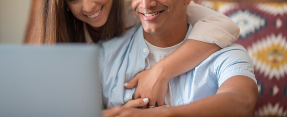Banner header image with young couple using laptop together at home. Boy and girl surfing the web and working with a computer. Concept of love and lifestyle. Woman hug man from back. Two person online