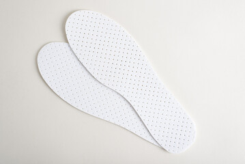 Fibrated white insoles for shoes on a light background, top view
